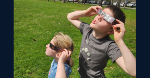 Two children with eclipse glasses on looking up at the eclipse