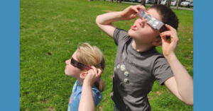 Two children with eclipse glasses on looking up at the eclipse